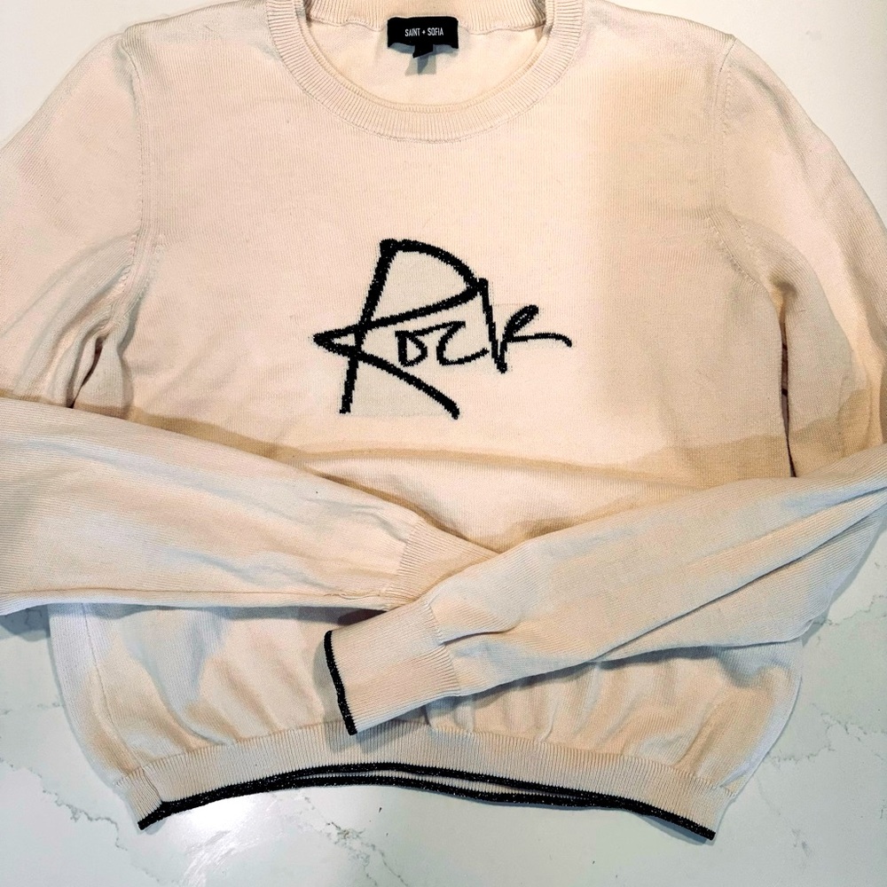 Cream light weight sweater with black and gold trim.